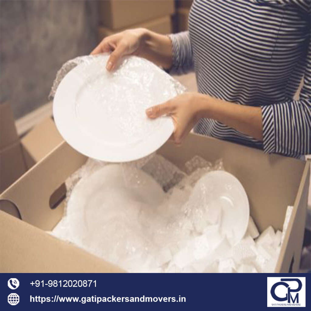 white plates wrapping in bubble wrap and placing inside gati packers and movers bangalore box before shifting